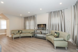 A modern living room with two sofas, a glass coffee table, and a wine rack.