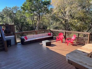 Relax on the deck with a bench and two chairs, surrounded by trees.