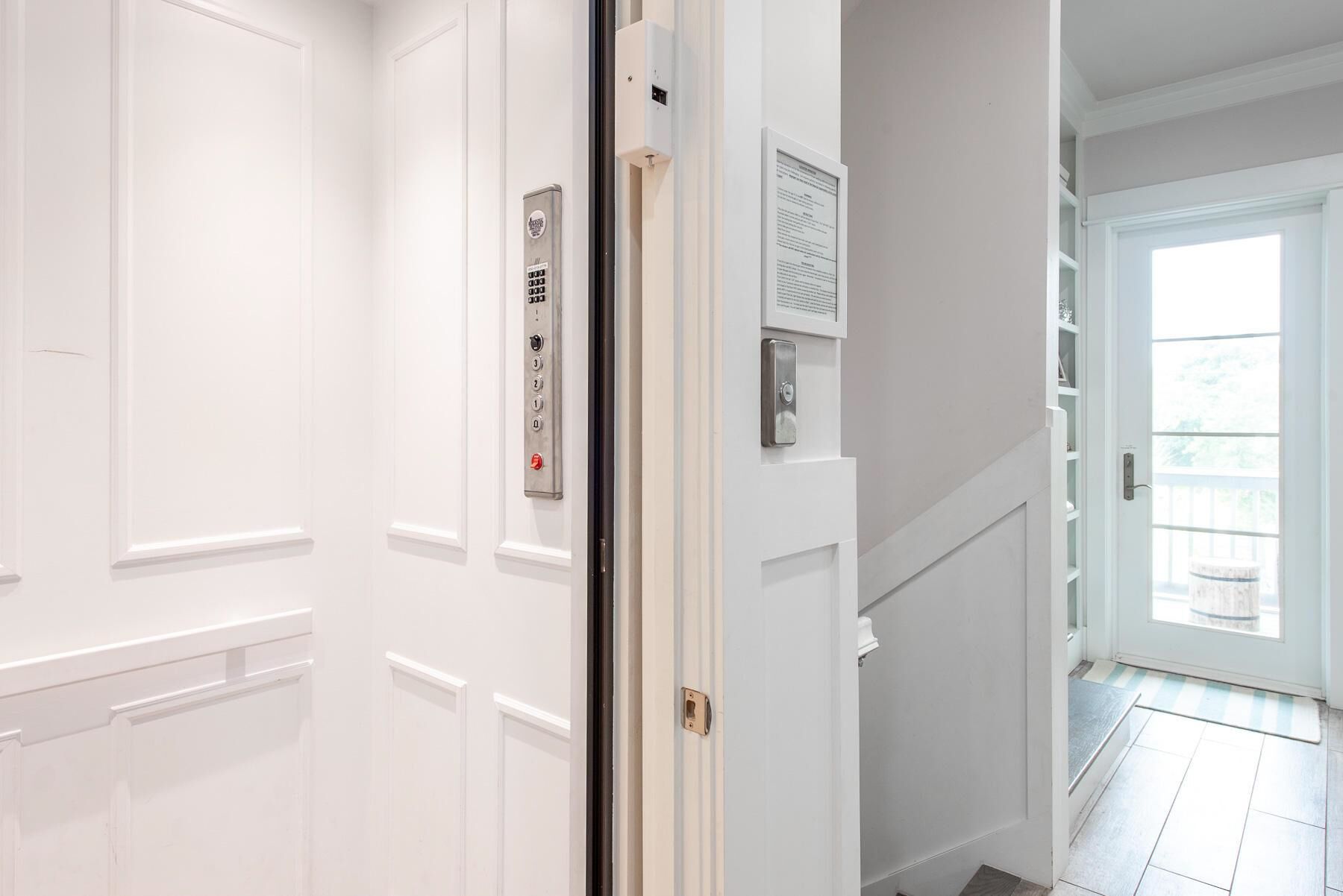 A hallway with white doors, a wall-mounted intercom, and a door with a peephole.