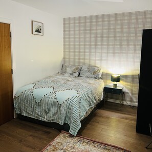 Cozy retreat with a neatly made bed, bedside table, and artwork.