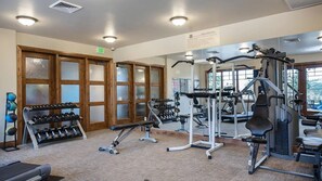 Ein Fitnessstudio mit Trainingsgeräten, Laufband und einer Hantelbank.