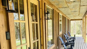 A covered porch with wooden railings, a black doormat, and a row of blue chairs. - Beautiful rustic cabin on the shores of Greer's Ferry Lake (Higden)