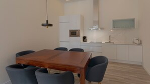 A modern kitchen with a dining area, featuring a wooden table and chairs, a built-in oven, and a microwave. - Fresh Velazquez Apartment D (Málaga)