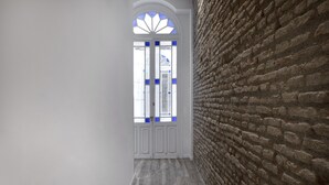 A hallway with a brick wall and a white door with blue accents. - Fresh Velazquez Apartment B (Málaga)