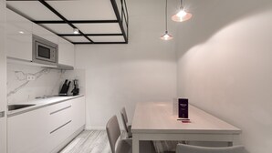 A modern kitchen with a microwave, cabinets, and a dining table with chairs. - Fresh Velazquez Apartment B (Málaga)