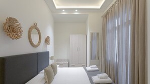 A modern hotel room with a large bed, a wardrobe, a mirror, and a view of the outdoors through sheer curtains. - Fresh Velazquez Apartment C (Málaga)
