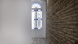 A hallway with a brick wall and a white door with blue accents. - Fresh Velazquez Apartment C (Málaga)