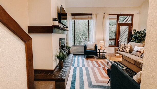 A modern living room with a sofa, a coffee table, and a fireplace. There is a staircase leading to another level. - 73SW - F/P - W/D - Sleeps 6 (Deming)