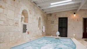 Een wellnessruimte met een jacuzzi, stenen muren en een houten plafond.