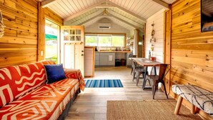 Interior acogedor de una cabaña con detalles de madera, un sofá, un banco, una mesa de comedor y una zona de cocina.