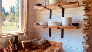 Una cocina con estantes de madera, una ventana y una encimera de madera.
