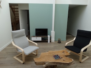 A living room with two chairs, a coffee table, a TV, and a small cabinet. - Duplex Le Rheun, luxury apartment 800 m from the beach (Douarnenez)