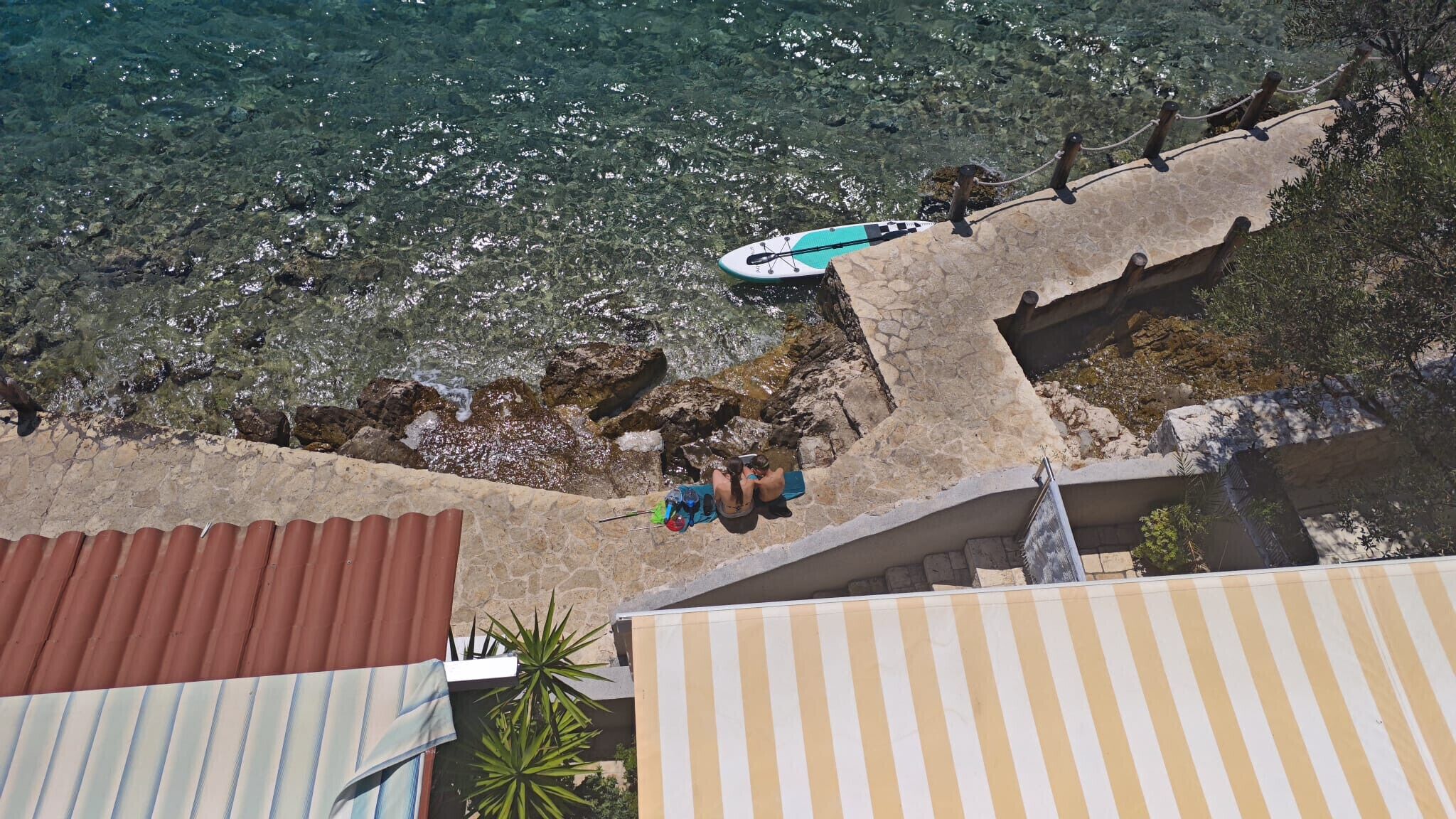 A coastal view with a clear sky, a rocky shoreline, and a paddleboard.