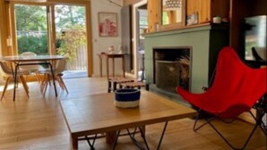 A modern living room with a wooden table, a red chair, and a fireplace. - Villa (Lège-Cap-Ferret)