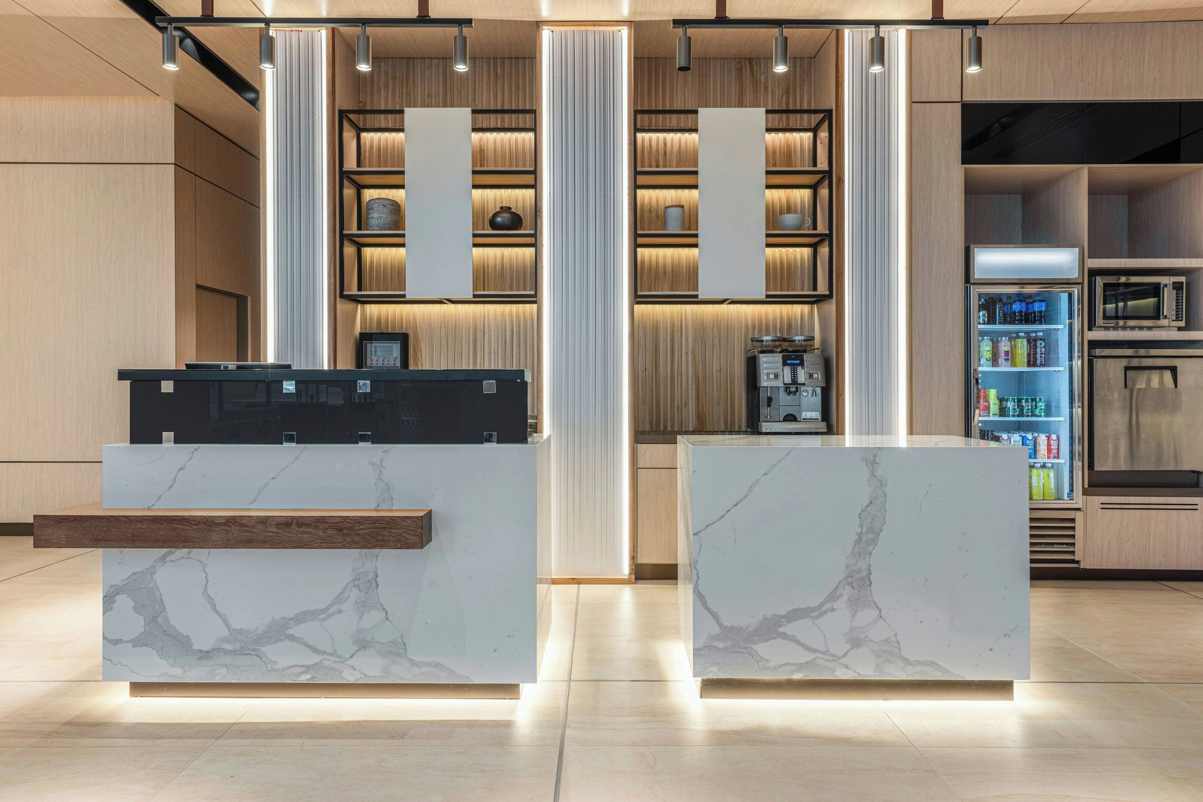 A modern kitchen with marble countertops, built-in appliances, and a central island.