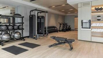 A modern gym with exercise equipment, treadmills, and dumbbells.