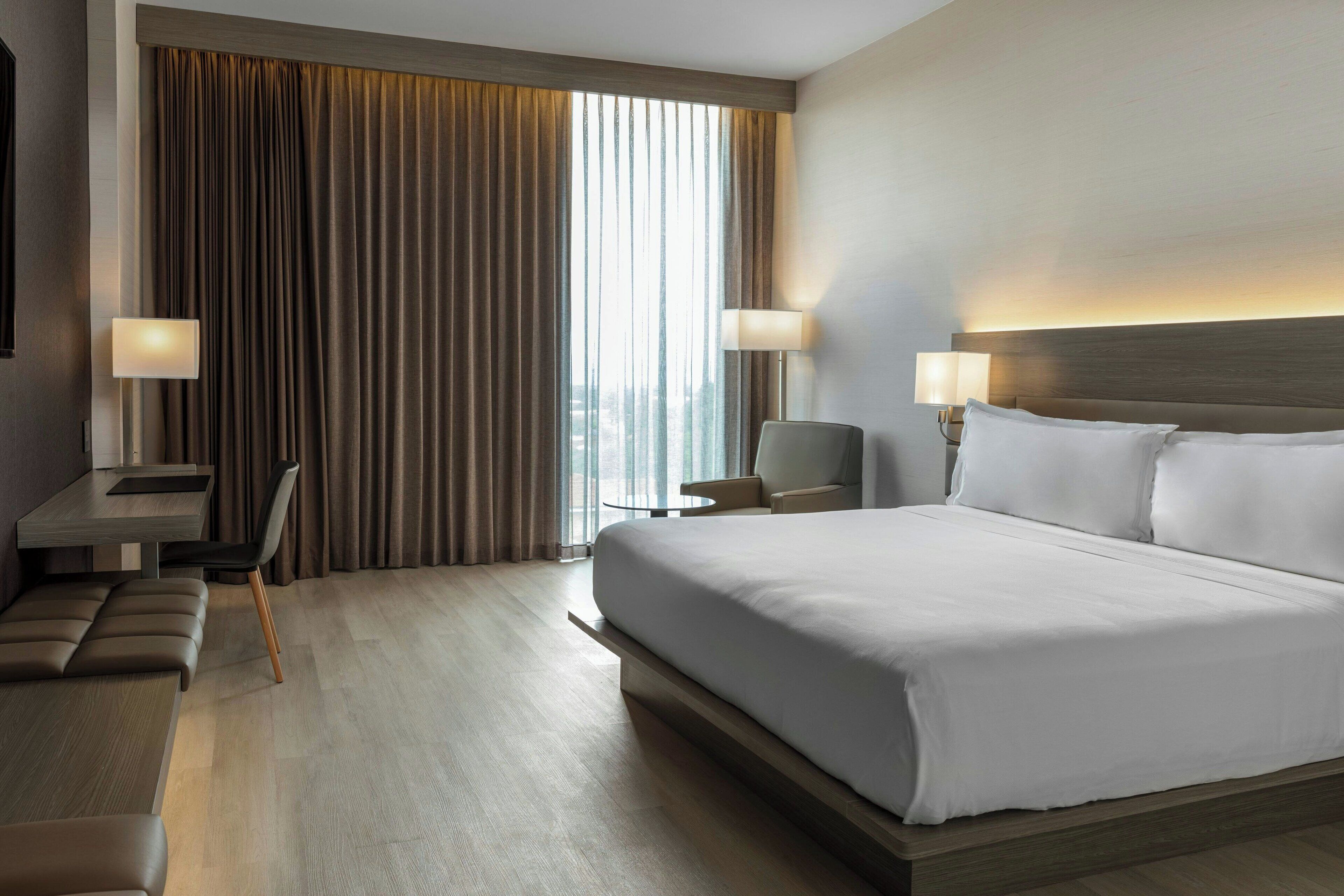 Une chambre d’hôtel moderne avec un grand lit, un bureau et une chaise.