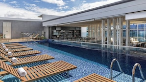 Un espace piscine avec des chaises longues et un bar.