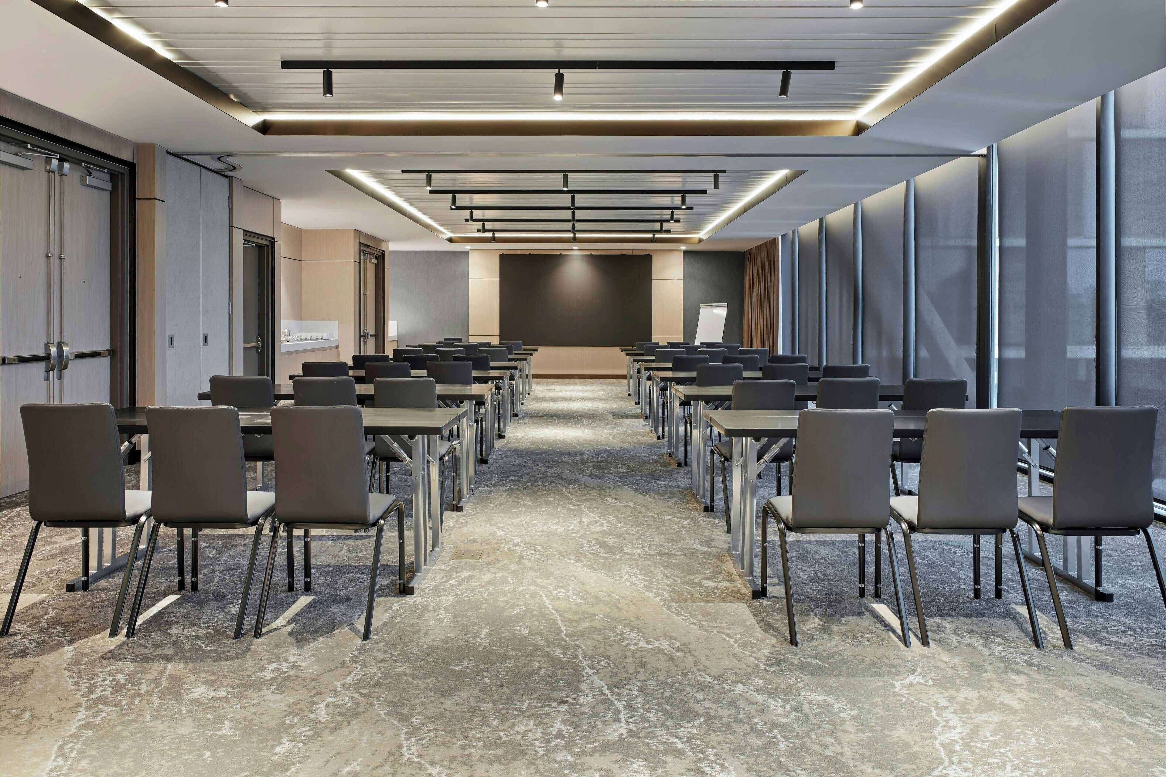 A conference room with a long table, chairs, and a presentation screen.