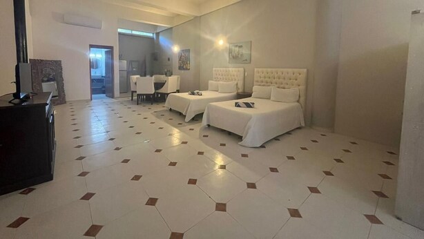 A hotel room with a tiled floor, two beds, a desk, and a chair.