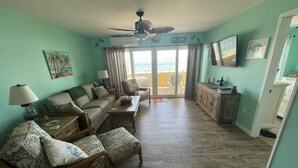 Un salon comprenant un canapé, des fauteuils, une table basse, un téléviseur et un ventilateur de plafond.