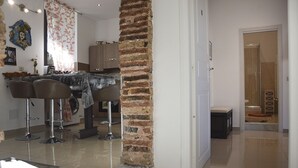 Une cuisine moderne avec des tabourets de bar, une colonne en briques et un coin repas comprenant une table et des chaises.