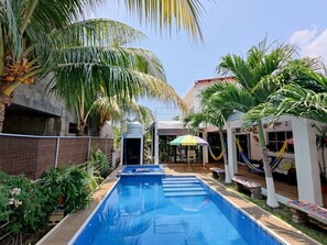 A swimming pool surrounded by palm trees and a hammock. - Traditional Colonial House, in private community 5 minutes from the Beachminutes (Canton San Blas)