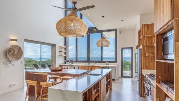 A modern kitchen with a large island, wooden cabinets, and large windows offering ocean views. - Luxurious Modern Villa with infinity pool- 5 min to the beach (Nosara, Costa Rica)