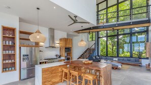 A spacious kitchen with a central island, wooden cabinetry, and a large window overlooking greenery. - Luxurious Modern Villa with infinity pool- 5 min to the beach (Nosara, Costa Rica)