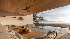 A modern outdoor seating area with a pool, wooden ceiling, and a view of the landscape. - Luxurious Modern Villa with infinity pool- 5 min to the beach (Nosara, Costa Rica)