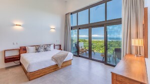 A bedroom with a large window, a bed, a nightstand, and a view of the ocean. - Luxurious Modern Villa with infinity pool- 5 min to the beach (Nosara, Costa Rica)