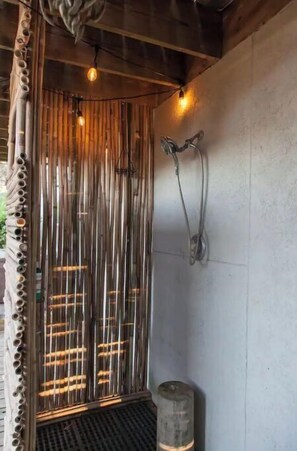 A shower area with vertical bamboo slats, a showerhead, and a water heater.