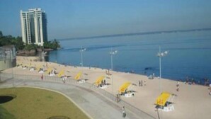 Una playa con sombrillas amarillas y un rascacielos al fondo.