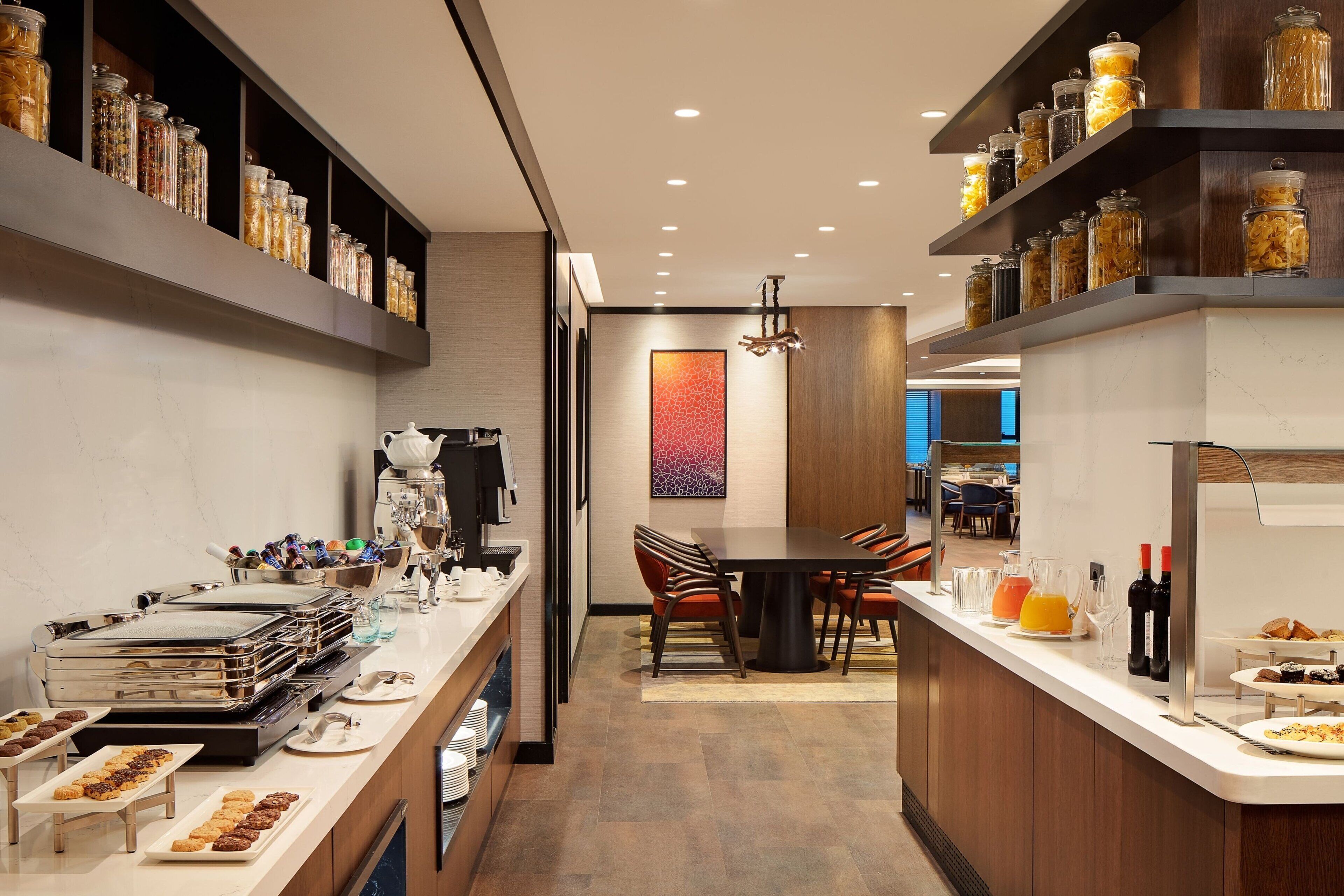 Una cocina moderna con una isla central, electrodomésticos de acero inoxidable y una variedad de alimentos exhibidos en estantes.