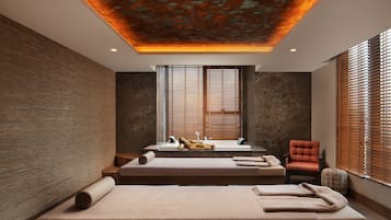Experience relaxation in this serene spa room with a massage table, chair, and warm ambiance.