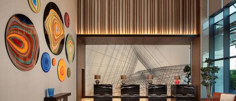 A modern lobby with abstract wall art, a seating area, and a large window.