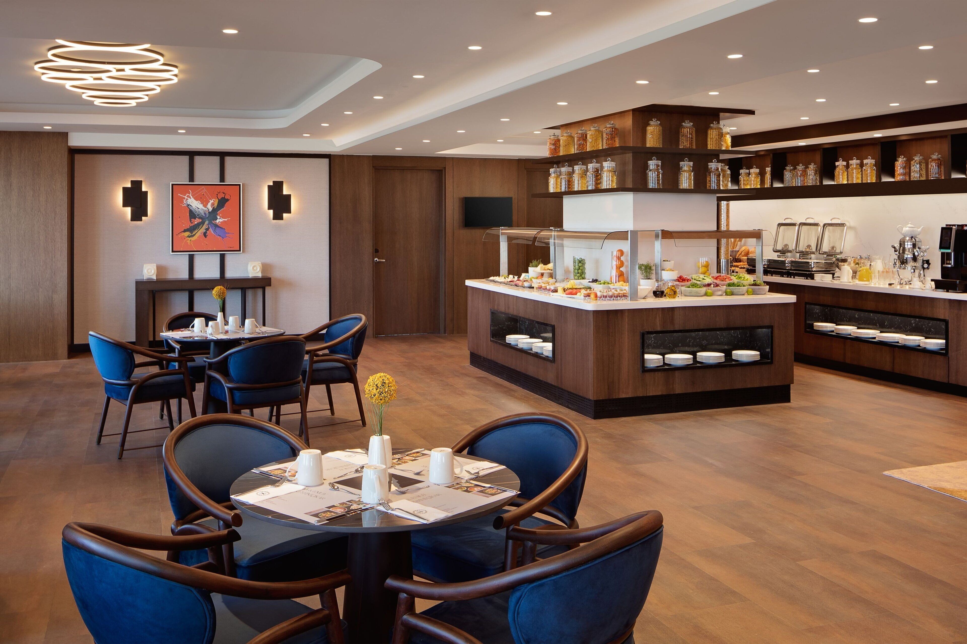 Un moderno vestíbulo de hotel con comedor, bufé y estación de café.