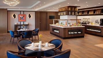 Un moderno vestíbulo de hotel con comedor, bufé y estación de café.