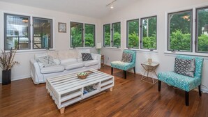 A spacious living room with a white sofa, a patterned armchair, and a coffee table. - Outdoor Oasis - Secluded Pool, Hot Tub, Fireplace (Cary)