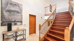 A staircase with wooden steps and a glass railing, leading to an upper floor.