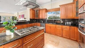 A modern kitchen with wooden cabinets, a stainless steel range, and a built-in oven.