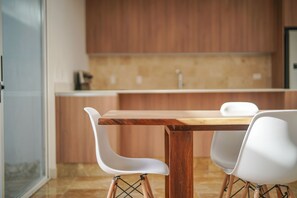 Une cuisine moderne avec des meubles de rangement en bois, une table en bois et des chaises blanches.