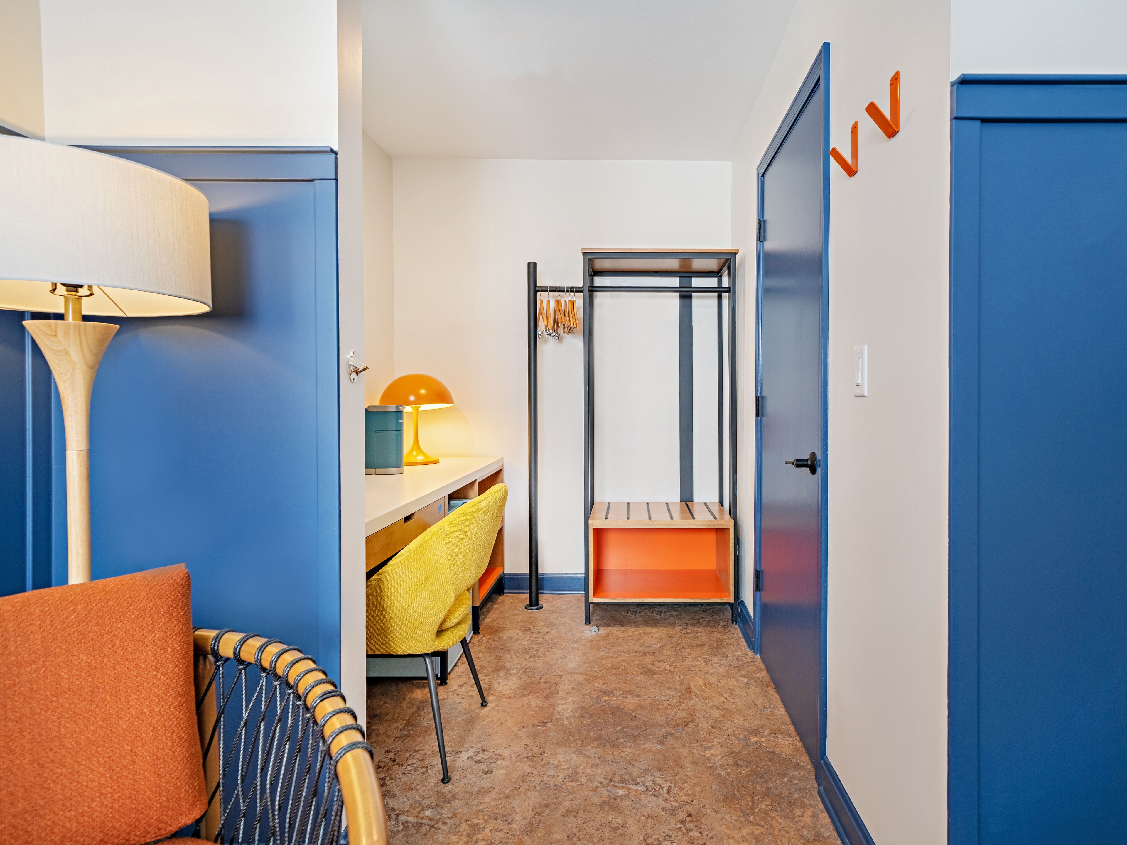 Ein Flurzimmer mit Bett, Schreibtisch, Stuhl und Kleiderschrank.