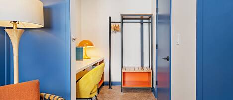 A hallway with a bed, a desk, a chair, and a wardrobe.