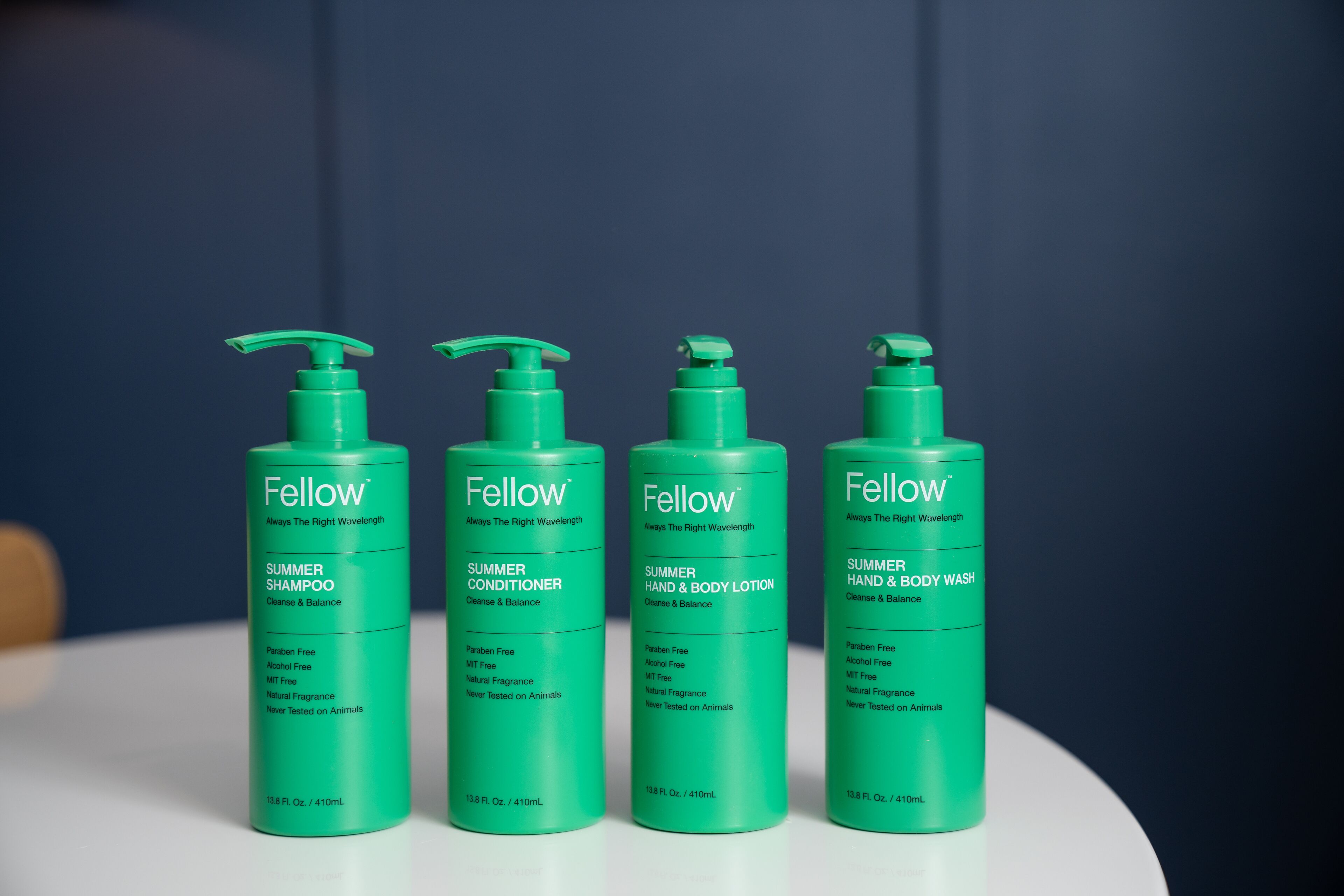 Four green bottles of Fellow products on a white surface.