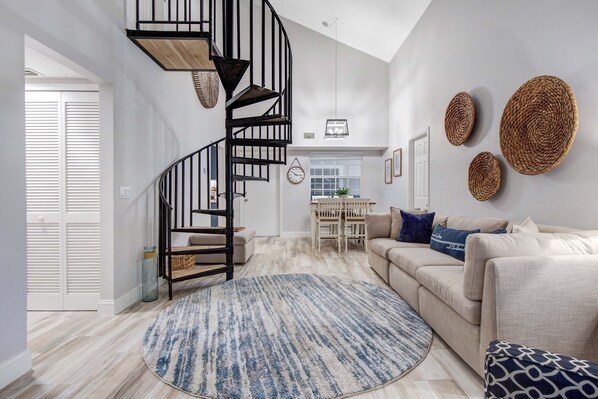 A spacious living area with a spiral staircase, a beige sofa, and a round rug.