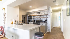 Une cuisine moderne dotée d’un îlot central, d’appareils électroménagers intégrés et d’un dosseret en marbre.