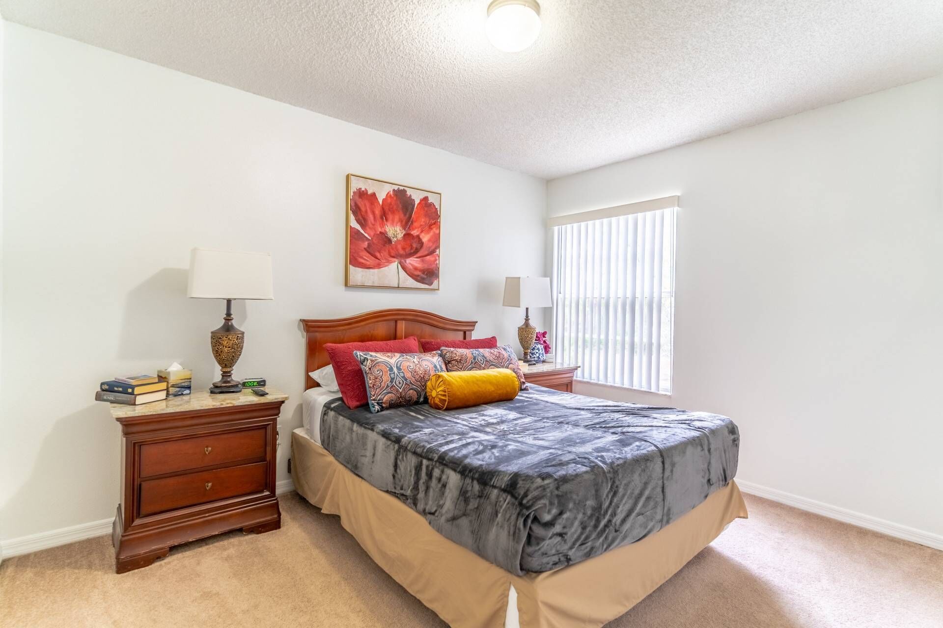 A bedroom with a bed, nightstands, a lamp, a painting, and a window.