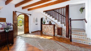 Ein geräumiges Foyer mit Steinwand, Holztreppe und einer großen offenen Tür zum Außenbereich.