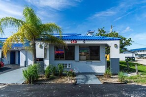 A single-story building with a blue roof, a 'VACANCY' sign, and a palm tree in front. - Howard Johnson by Wyndham Sebring (Sebring)